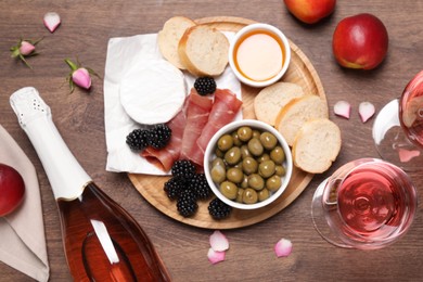 Photo of Delicious rose wine and snacks on wooden table, flat lay