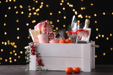 Photo of Wooden crate with Christmas gift set on grey table against festive lights