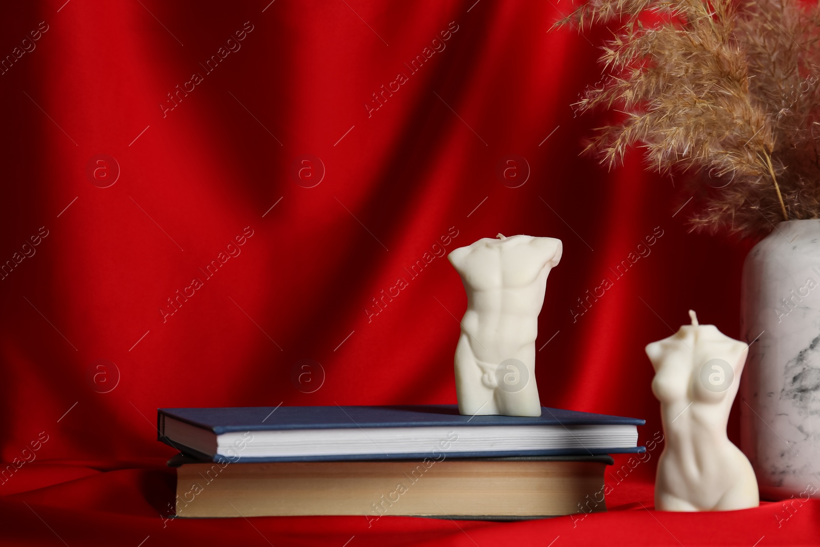 Photo of Composition with beautiful female and male body shaped candles on red fabric