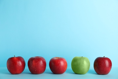Photo of Row of red apples with green one on color background. Be different
