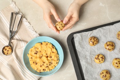Photo of Woman making delicious chocolate chip cookies at light grey table, top view