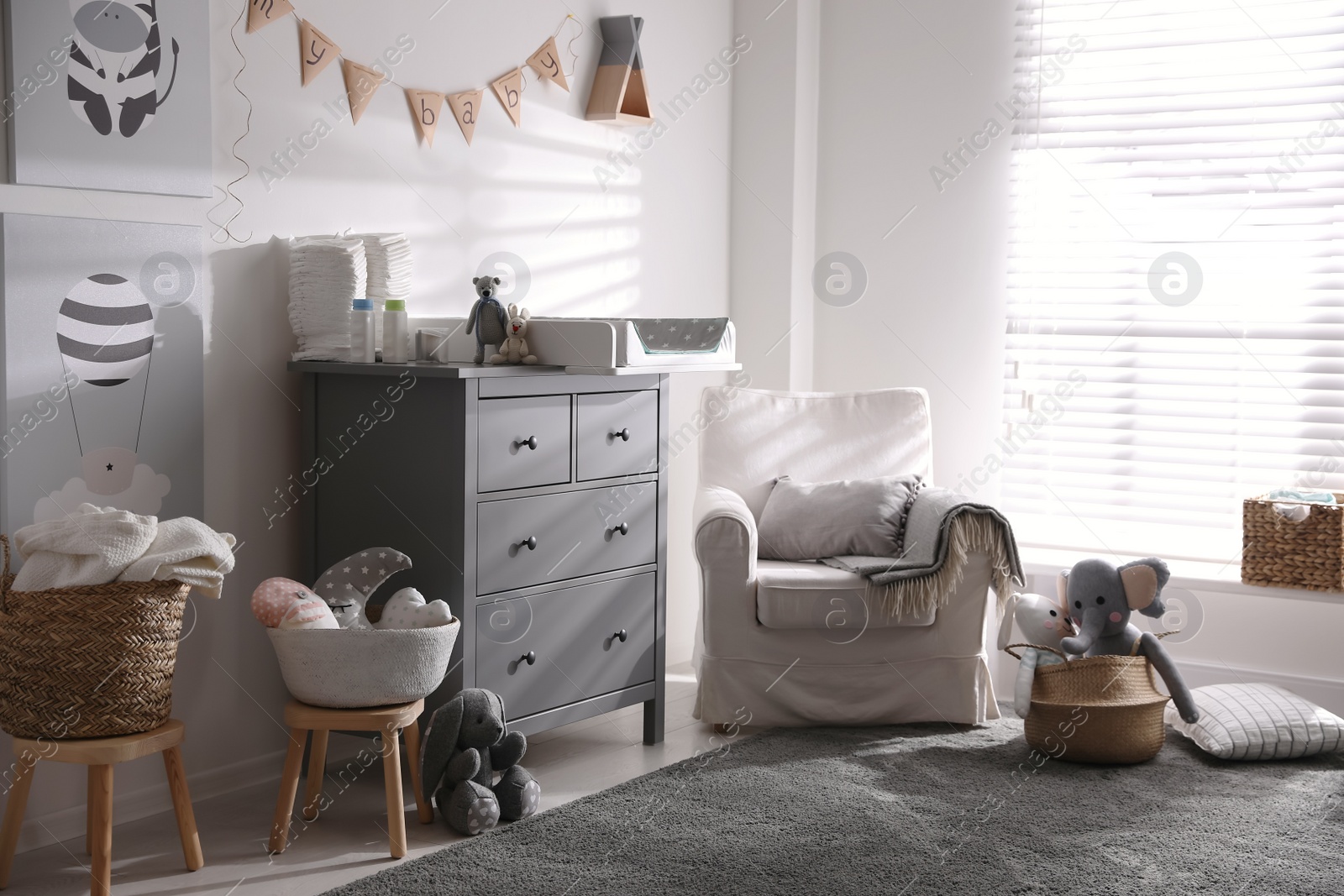 Photo of Chest of drawers with changing tray and pad in baby room. Interior design