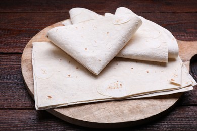 Photo of Delicious folded Armenian lavash on wooden table, closeup