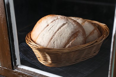 Fresh homemade bread in wicker basket, view through window