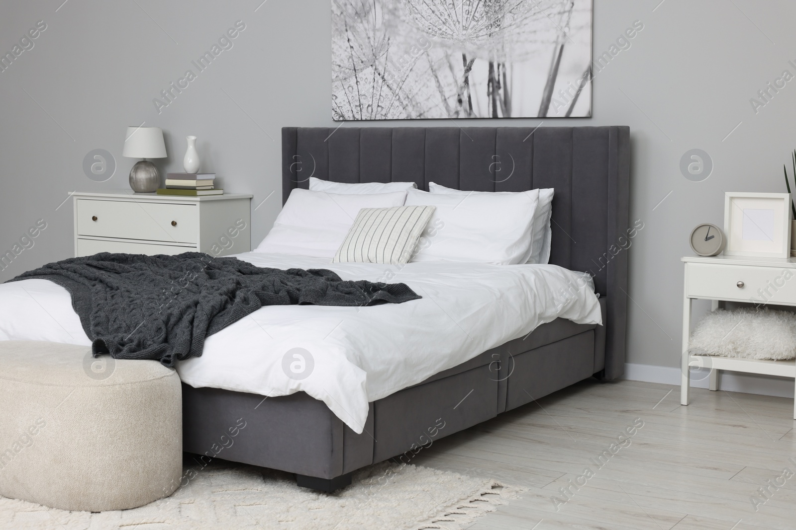 Photo of Stylish bedroom interior with large comfortable bed and ottoman