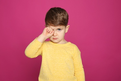 Photo of Little boy rubbing eye on color background. Annoying itch