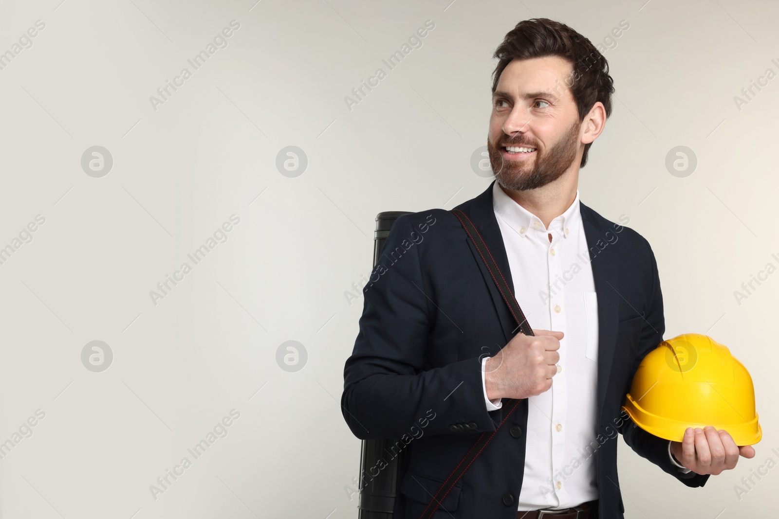 Photo of Architect with drawing tube and hard hat on gray background, space for text