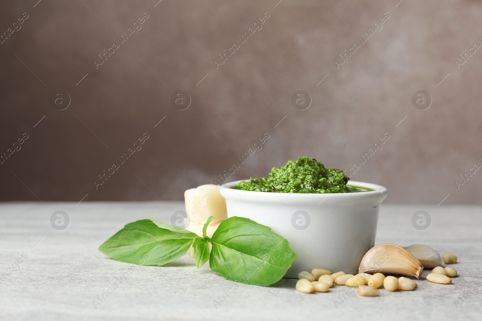 Photo of Composition with bowl of pesto sauce on table. Space for text