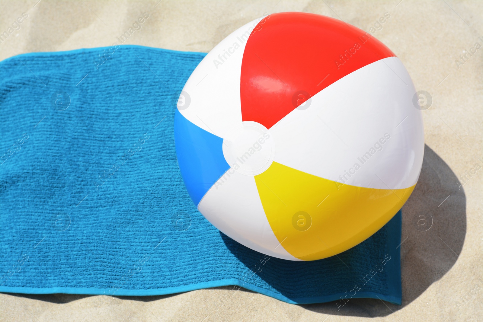 Photo of Blue towel and colorful beach ball on sand