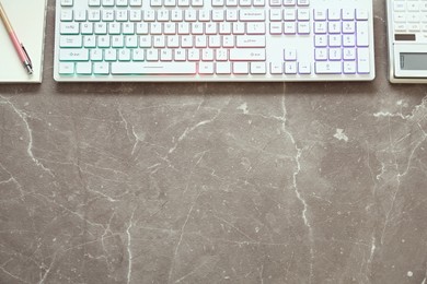 Photo of Modern RGB keyboard and stationery on grey table, flat lay. Space for text