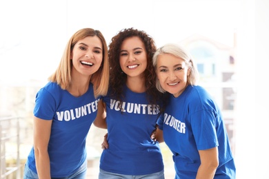 Portrait of happy female volunteers in uniform indoors