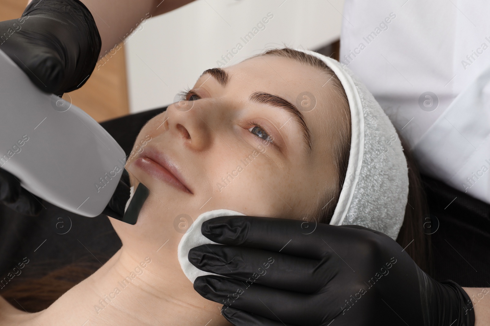 Photo of Cosmetologist using ultrasonic scrubber, closeup. Client having cleansing procedure indoors