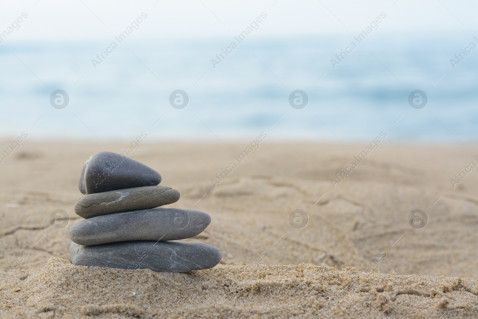 Photo of Stack of stones on sandy beach near sea, space for text