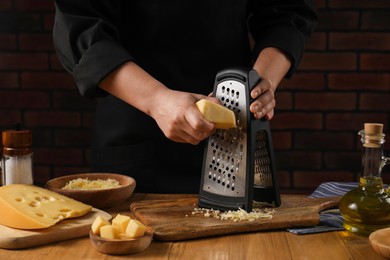 Woman grating cheese at wooden table, closeup