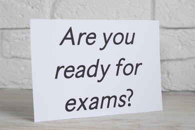 Photo of Paper with question Are you ready for exams on white wooden table, closeup