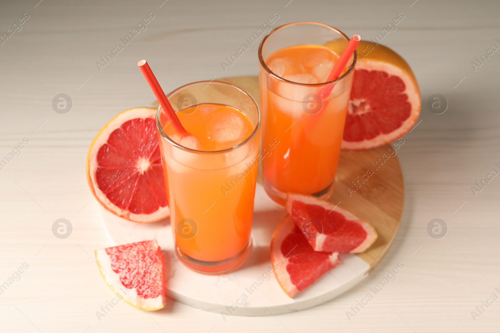 Photo of Tasty freshly made grapefruit juice and fruits on white wooden table