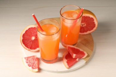 Photo of Tasty freshly made grapefruit juice and fruits on white wooden table