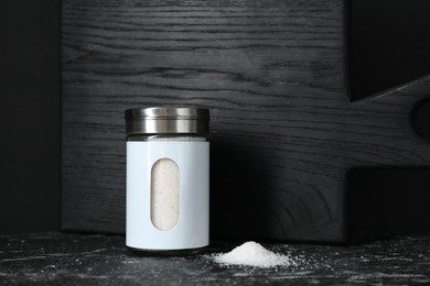 Stylish shaker with salt on dark table