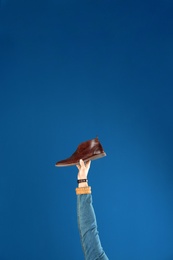 Photo of Young man holding comfortable stylish shoe on blue background, closeup