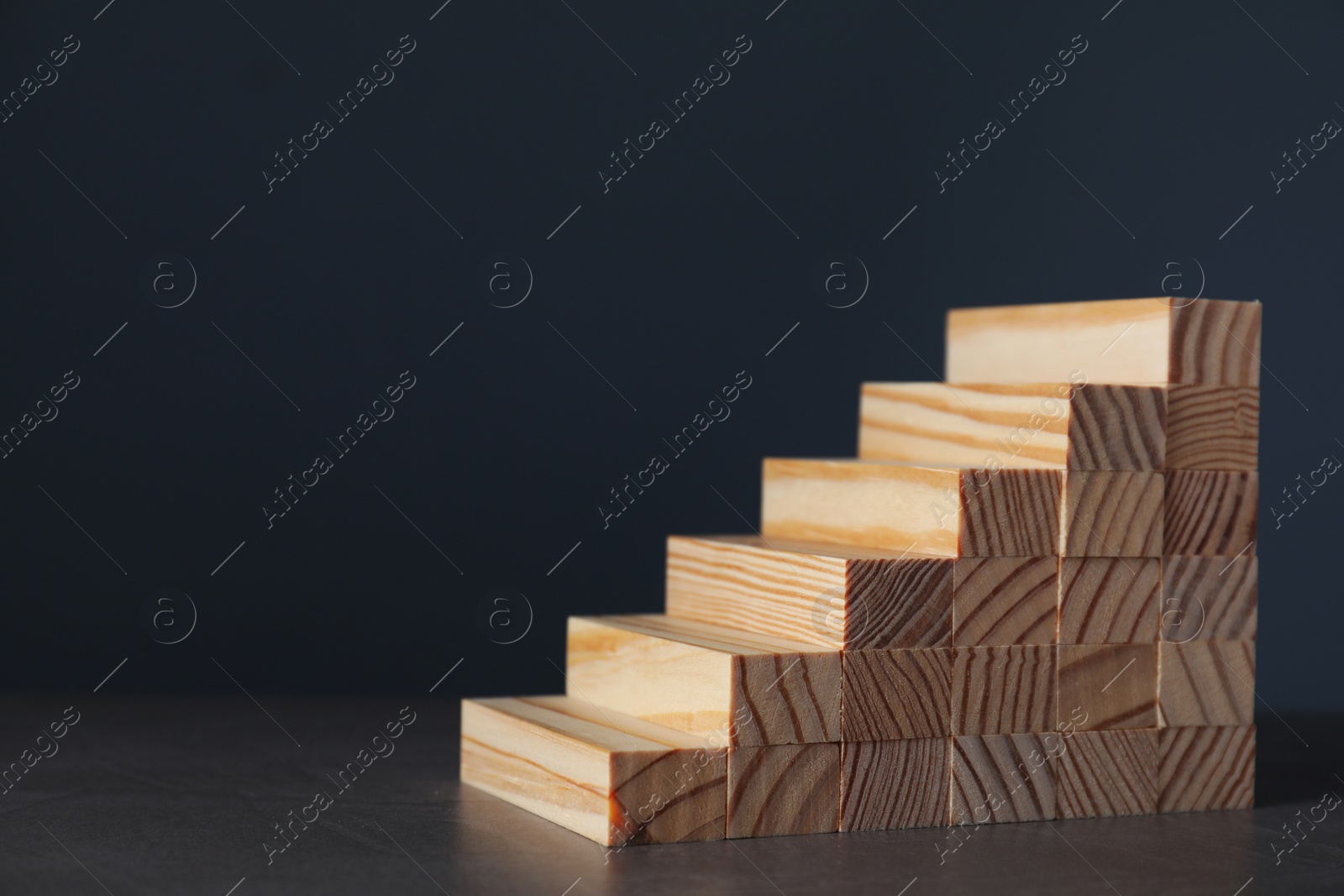 Photo of Steps made with wooden blocks on dark background, space for text. Career ladder