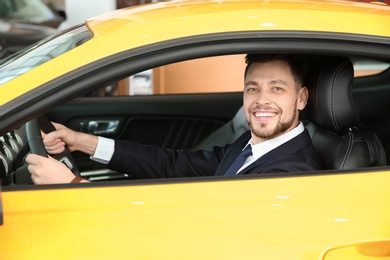 Young businessman sitting in driver's seat of auto. Buying new car