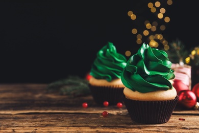 Photo of Delicious cupcakes with green cream on wooden table. Space for text