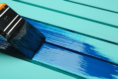 Photo of Brush and blue paint stroke on wooden background, closeup. Space for text