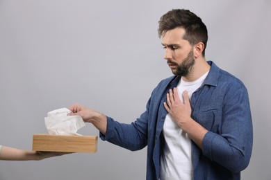 Photo of Sick man taking tissue on grey background. Cold symptoms