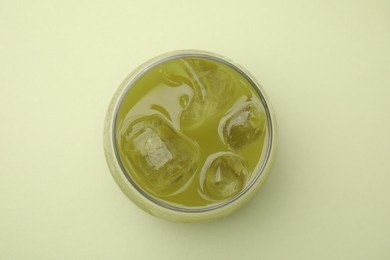 Glass of delicious iced matcha tea on green background, top view