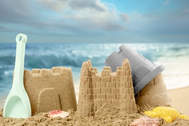 Sand castles with toys on ocean beach, closeup. Outdoor play