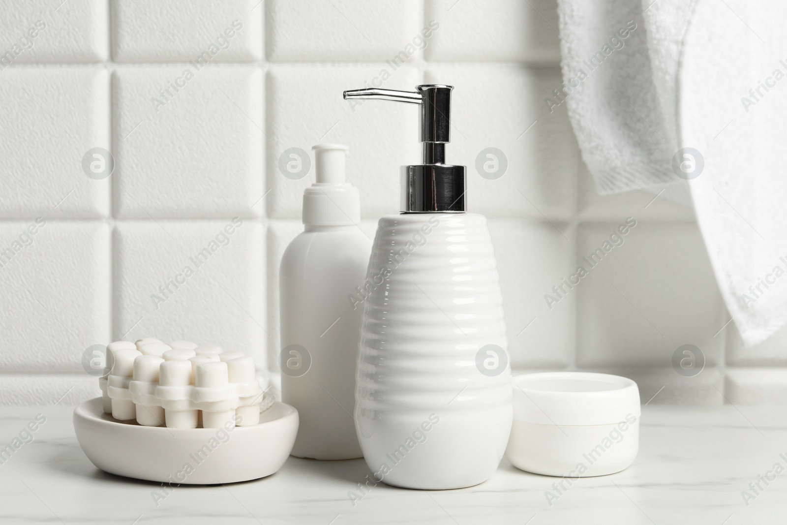 Photo of Different bath accessories and personal care products on white table near tiled wall