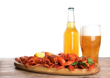 Delicious red boiled crayfishes and beer on wooden table against white background