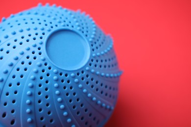Photo of Laundry dryer ball on red background, closeup. Space for text