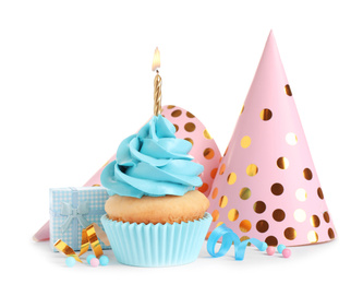 Delicious birthday cupcake with candle, gift and party caps on white background