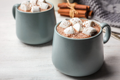 Cups of delicious hot cocoa with marshmallows on white wooden table