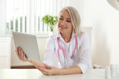 Photo of Doctor consulting patient using video chat on tablet in clinic