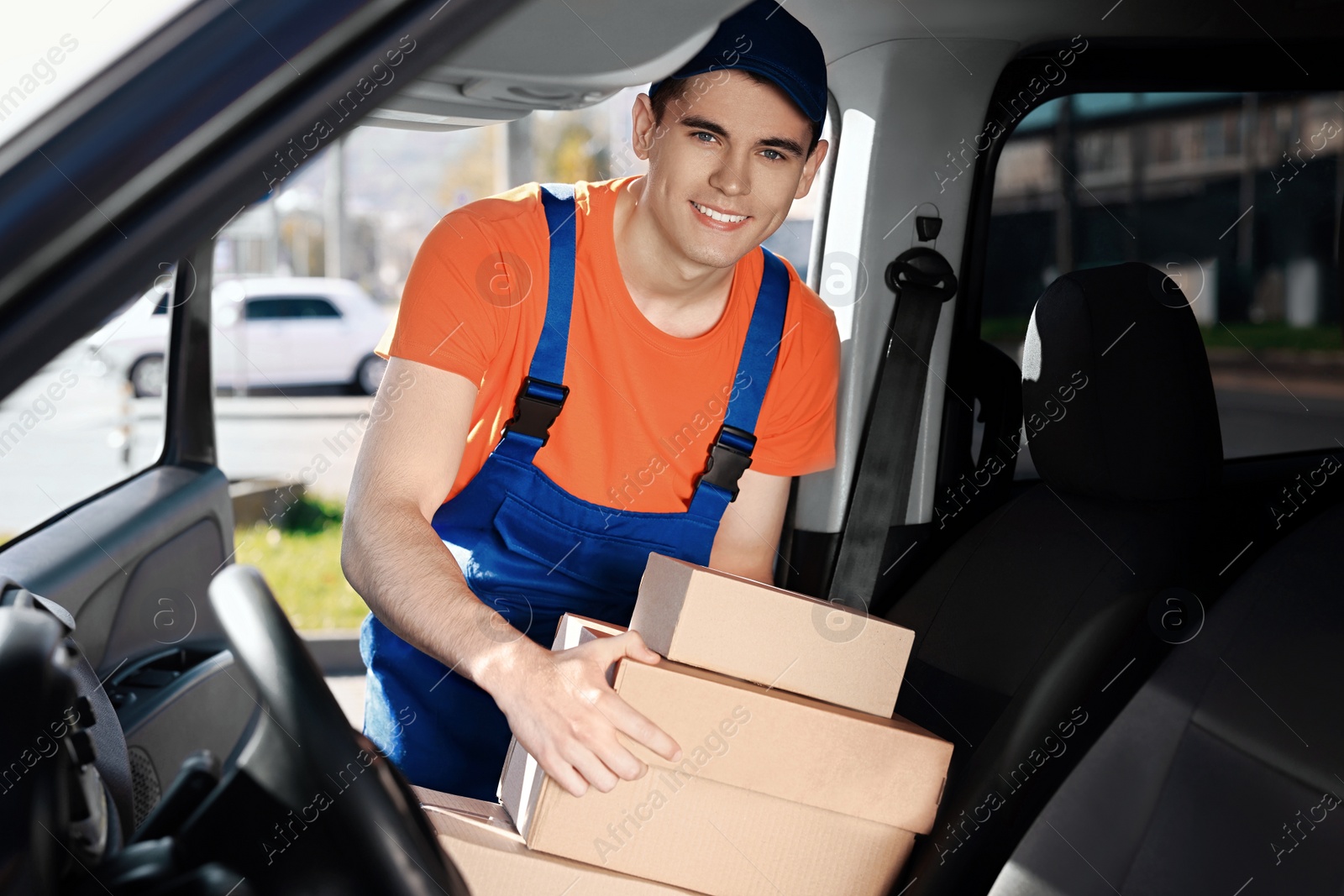 Photo of Courier taking parcels from car. Delivery service