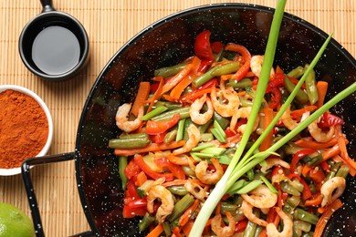 Shrimp stir fry with vegetables in wok and ingredients on table, flat lay