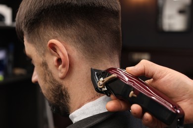 Photo of Professional hairdresser making stylish haircut in barbershop, closeup