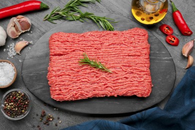 Raw fresh minced meat and ingredients on black wooden table, flat lay