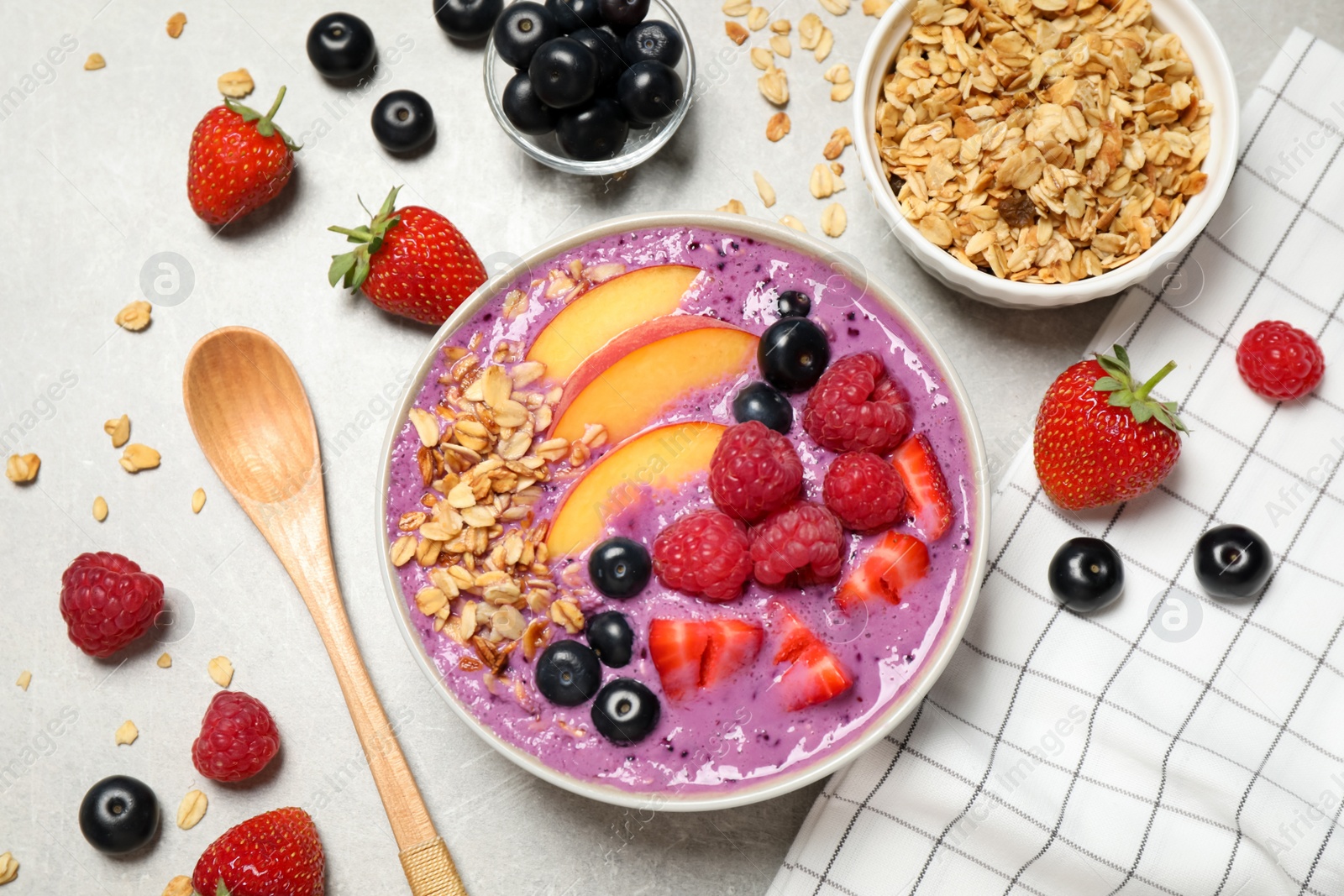 Photo of Delicious acai smoothie in bowl and ingredients on light grey table, flat lay