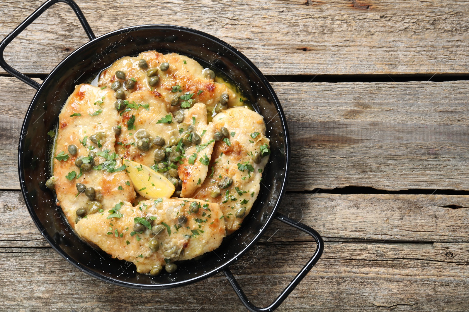 Photo of Delicious chicken piccata with herbs on wooden table, top view. Space for text