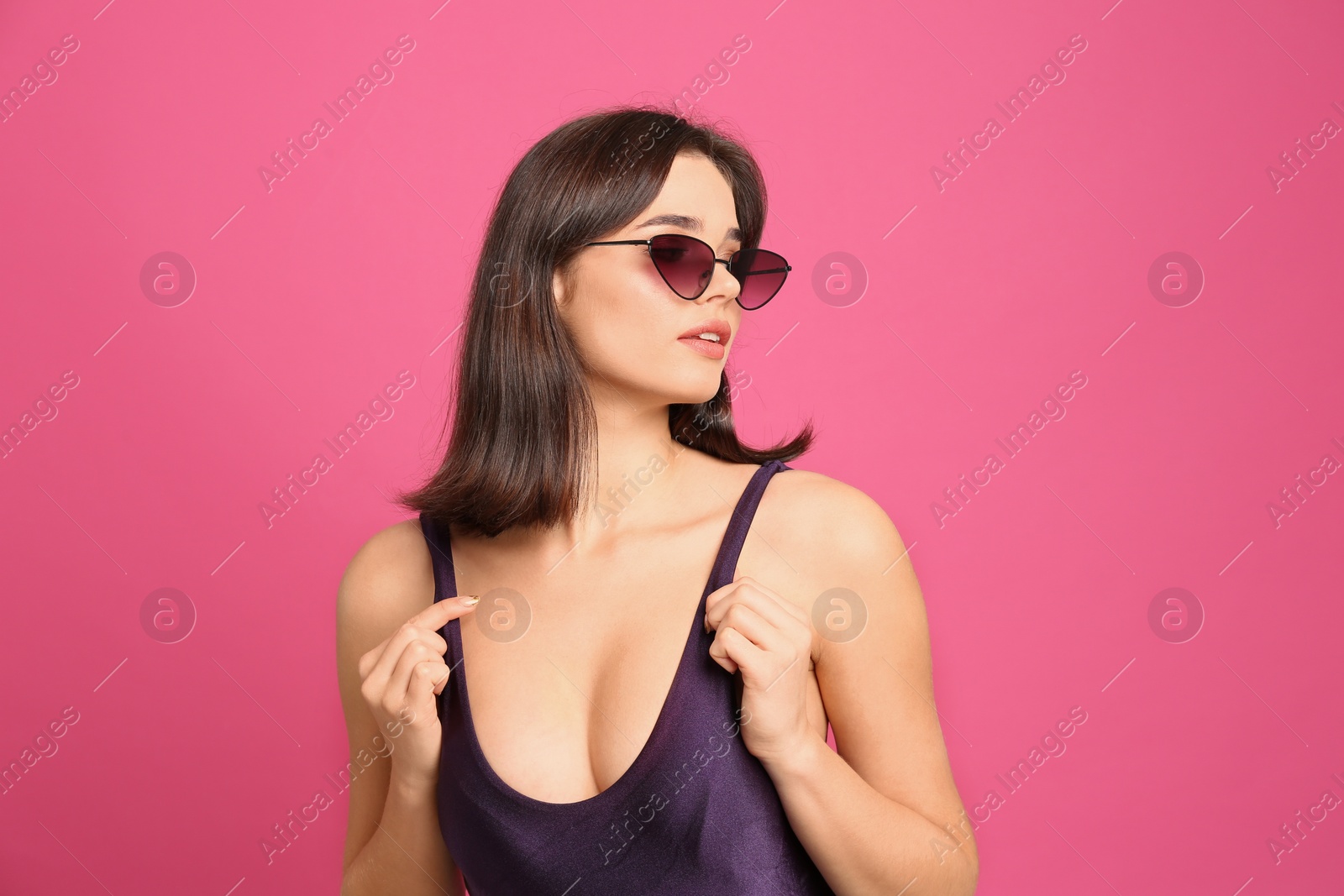 Photo of Beautiful woman in stylish swimsuit and sunglasses on pink background