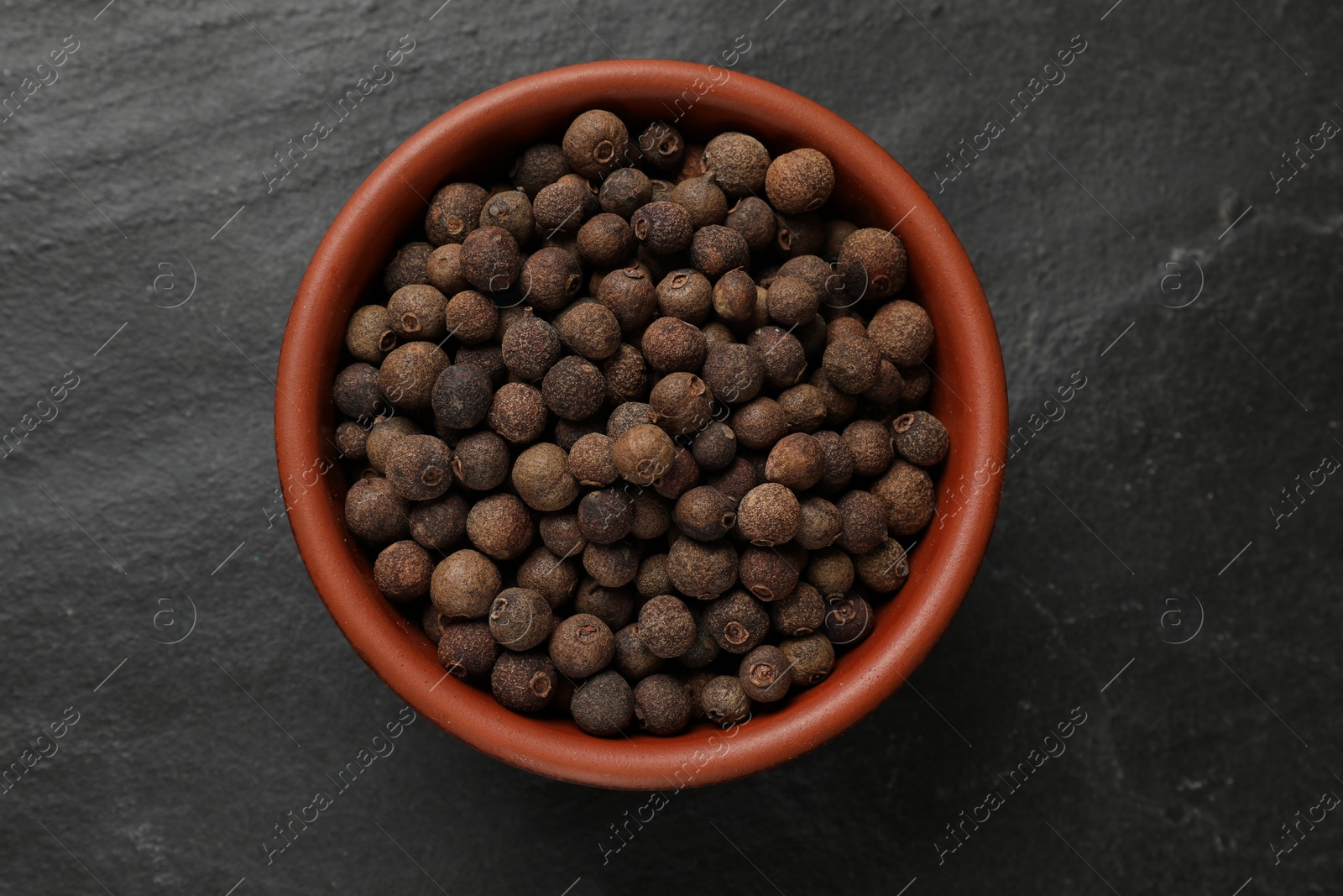 Photo of Dry allspice berries (Jamaica pepper) on black table, top view