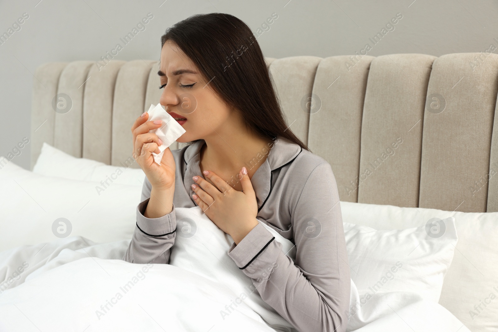 Photo of Sick young woman with tissue in bed at home