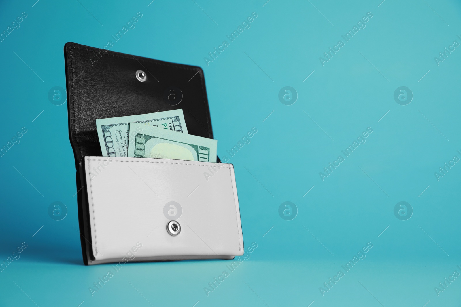 Photo of Open leather purse with dollar banknotes on light blue background. Space for text