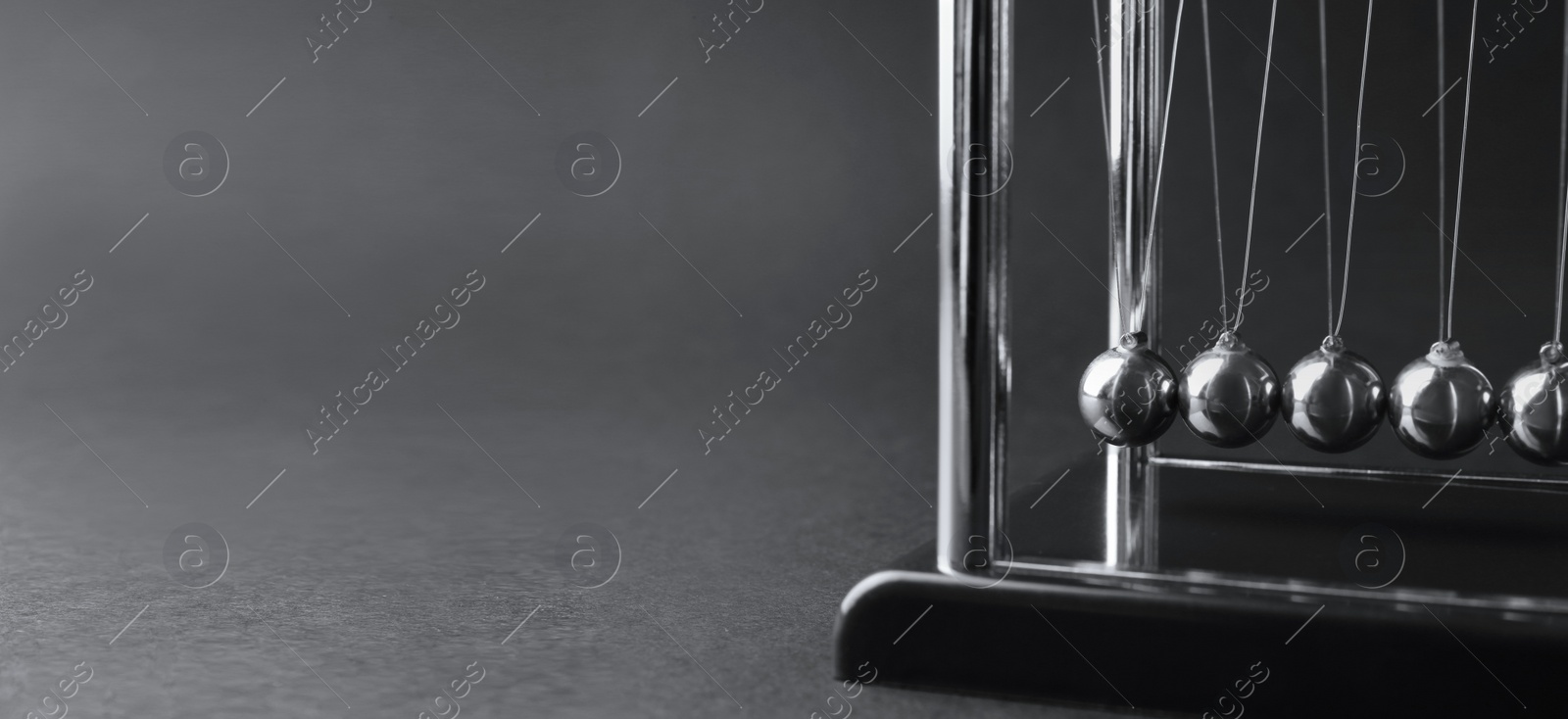 Photo of Newton's cradle on dark background, closeup. Physics law of energy conservation