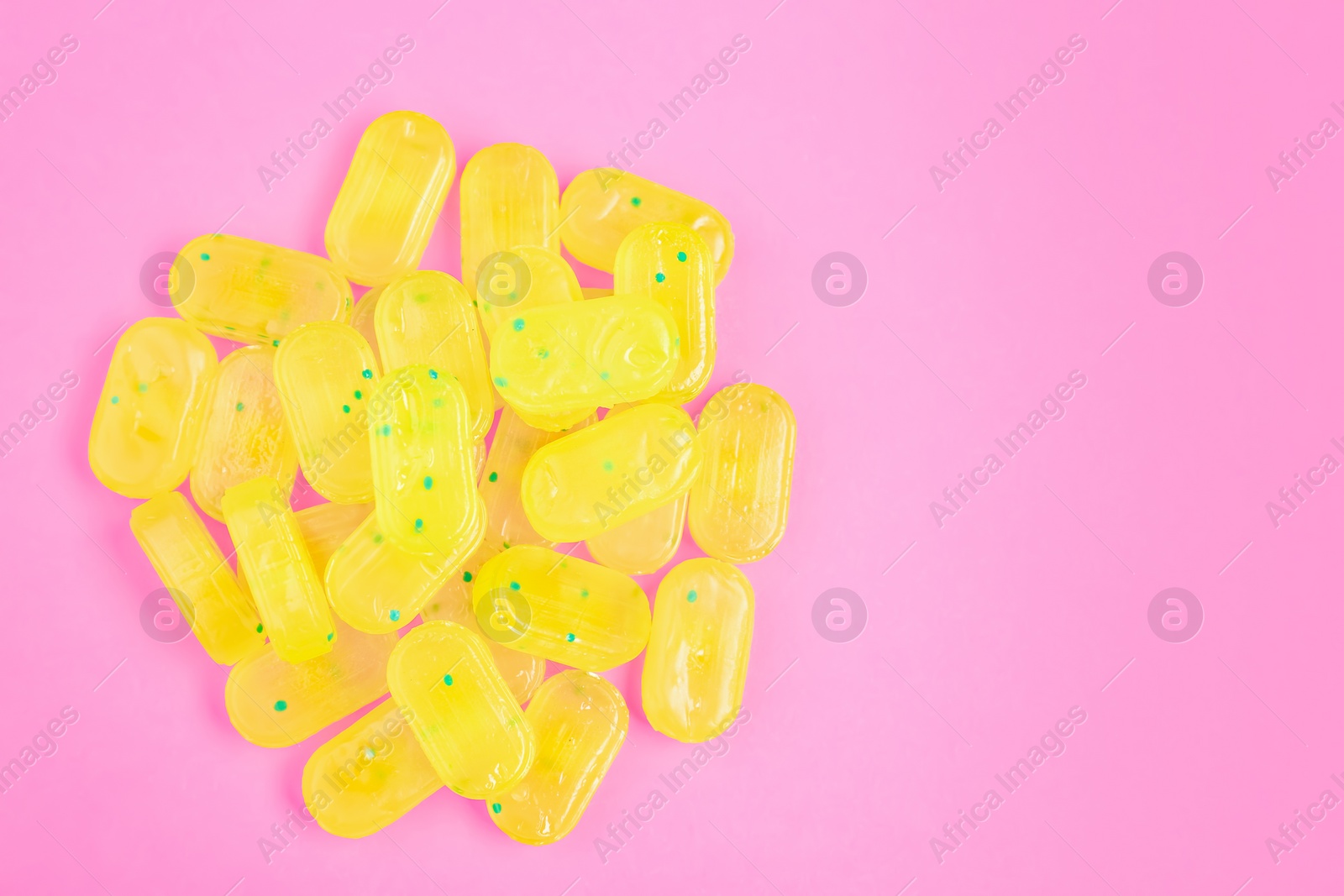 Photo of Many delicious lemon drops on pink background, flat lay. Space for text