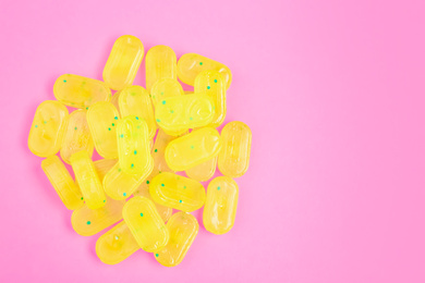 Photo of Many delicious lemon drops on pink background, flat lay. Space for text