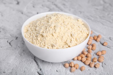 Photo of Chickpea flour in bowl and seeds on light grey textured table
